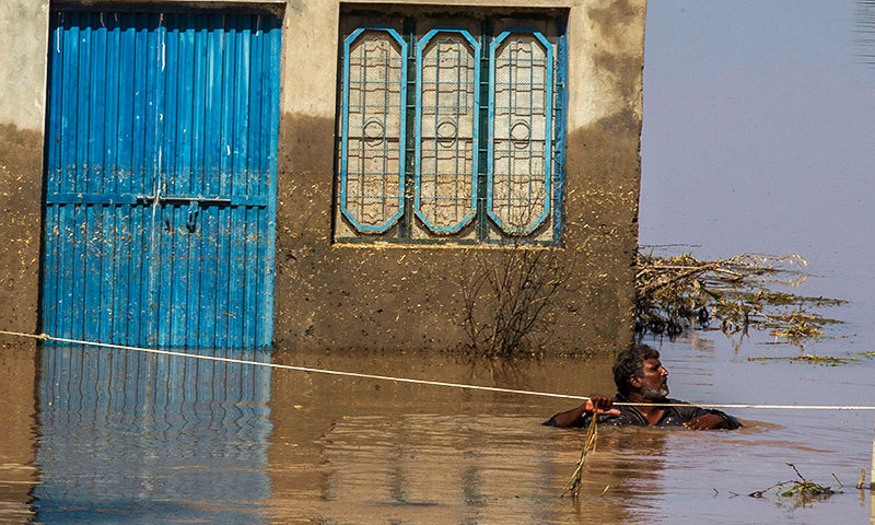 A man uses a rope while he wades through a flooded field beside his house following heavy rain in Pindi Bhattian, Punjab Province. -Photo by Reuters A man uses a rope while he wades through a flooded field beside his house following heavy rain in Pindi Bhattian, Punjab Province. -Photo by Reuters