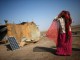 A labourer, who works in a salt pan, covers her face beside a solar panel outside a shelter in Little Rann of Kutch in the western Indian state of Gujarat March 2, 2014. REUTERS/Ahmad Masood